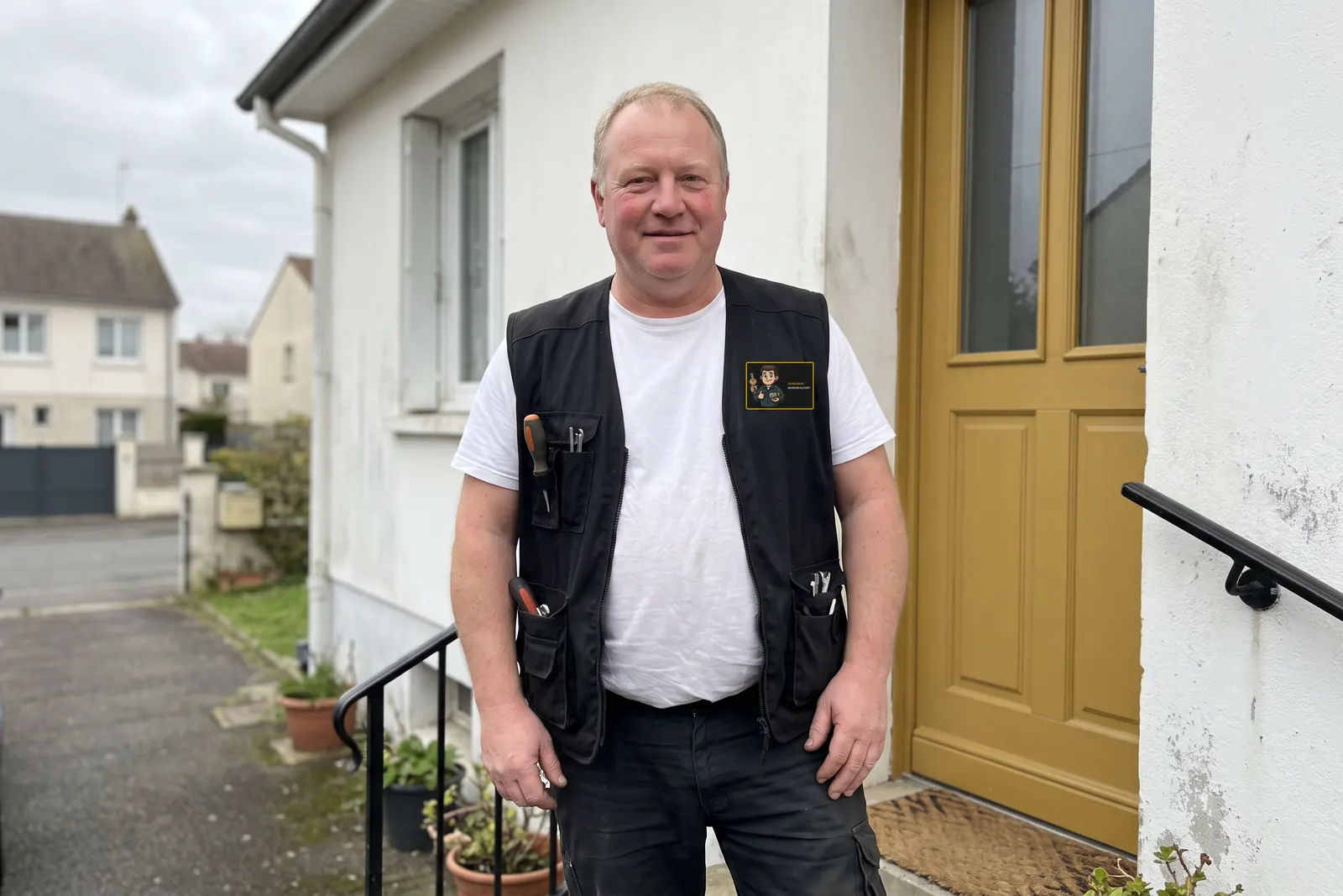 Votre serrurier à Maisons-Alfort devant la porte d'une maison, gilet de travail avec l'écusson Serrurier Maisons-Alfort